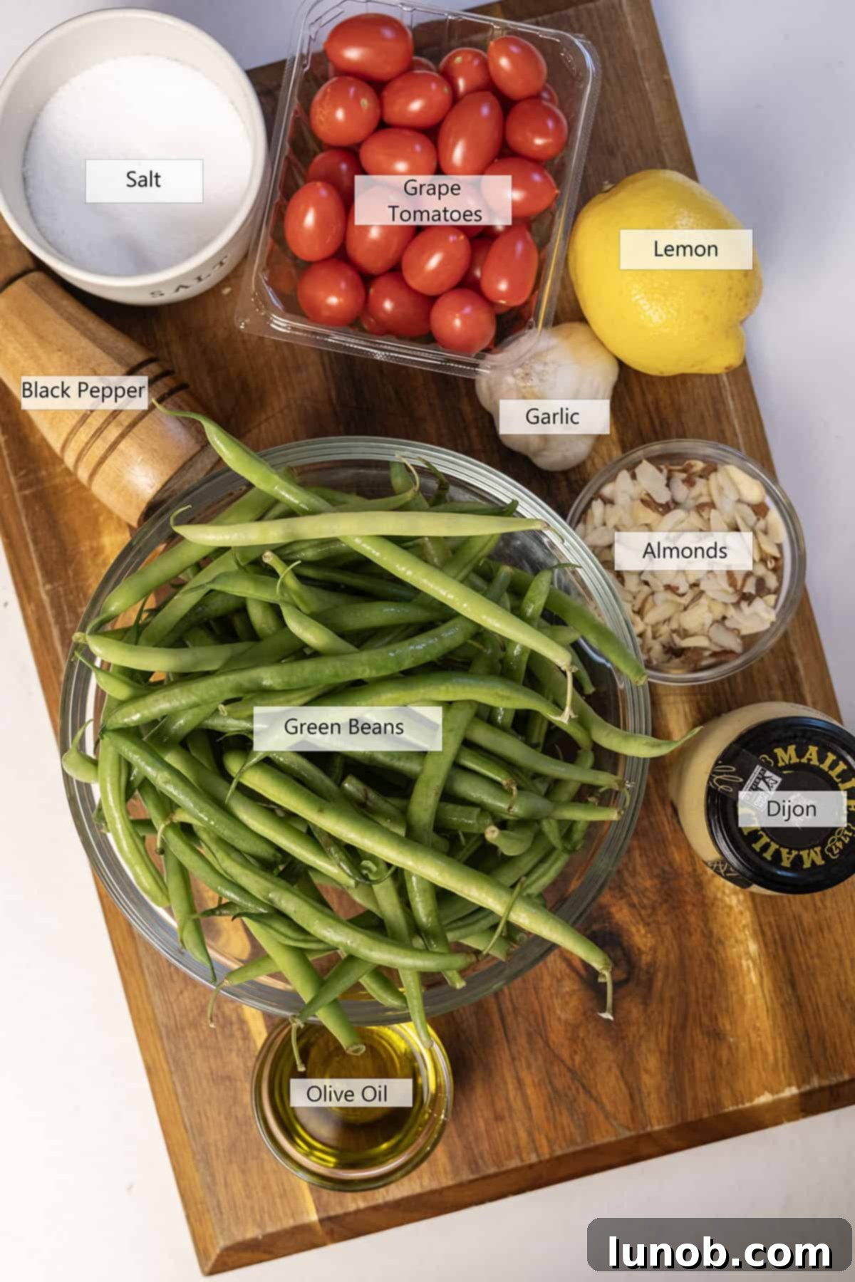 Fresh ingredients for Italian green bean salad including green beans, cherry tomatoes, and almonds