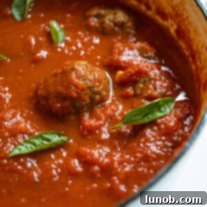 Nonna's Sunday Gravy 13 A large pot of Authentic Italian Sunday Sauce, brimming with meatballs and sausages, ready for serving.