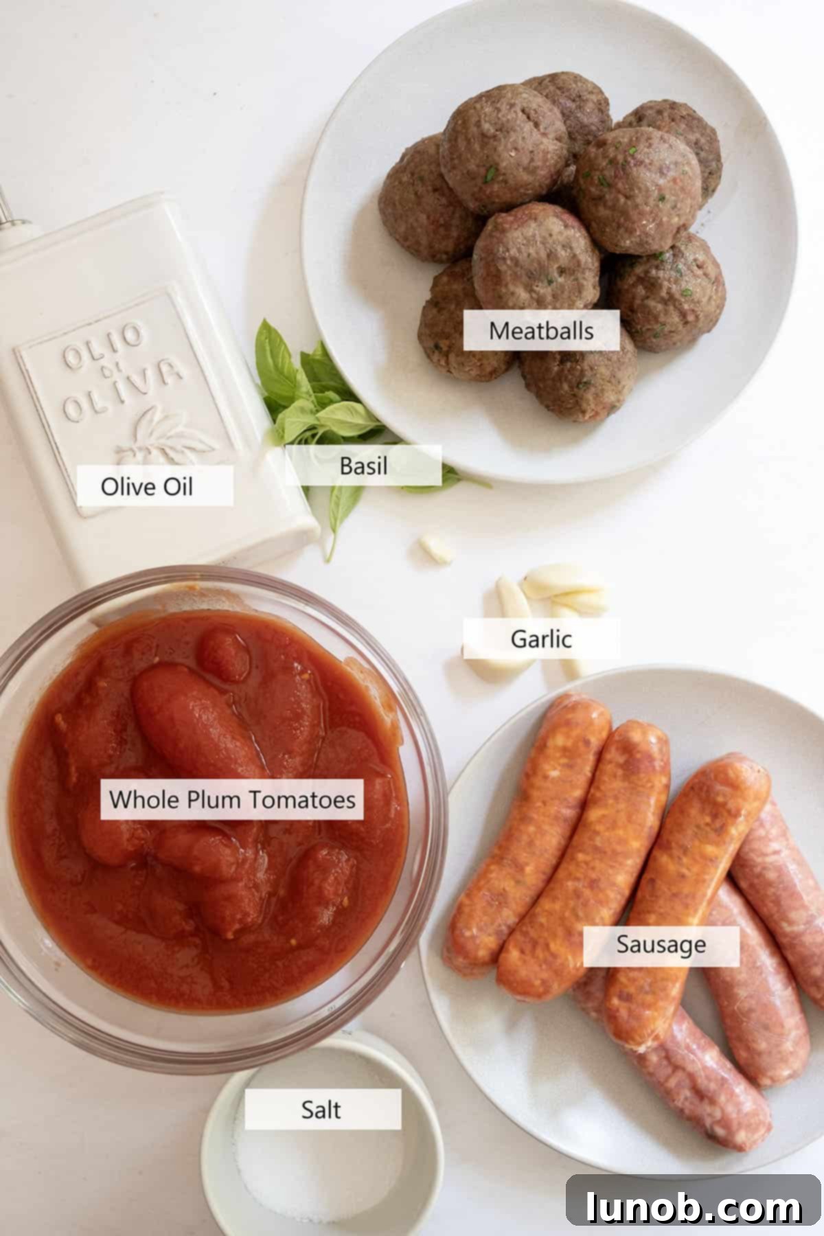 Nonna's Sunday Gravy 3 Fresh ingredients laid out for Sunday sauce preparation, including garlic, basil, canned tomatoes, and olive oil.