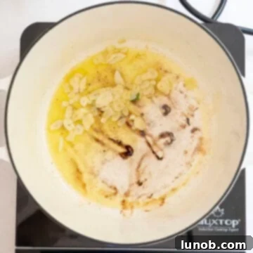 Nonna's Sunday Gravy 7 Thinly sliced garlic being sautéed in extra virgin olive oil in a large pot, filling the kitchen with its aroma.