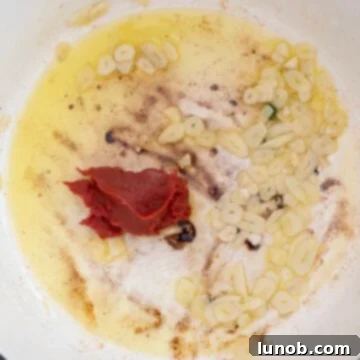 Nonna's Sunday Gravy 8 Tomato paste caramelizing in a pot, separate from the garlic, developing a rich, deep red color.