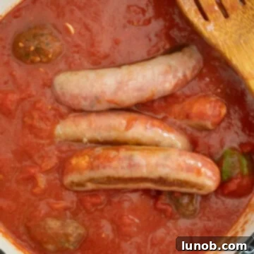 Nonna's Sunday Gravy 10 A large pot of Sunday sauce simmering gently, with meatballs and sausages nestled in the rich tomato base.