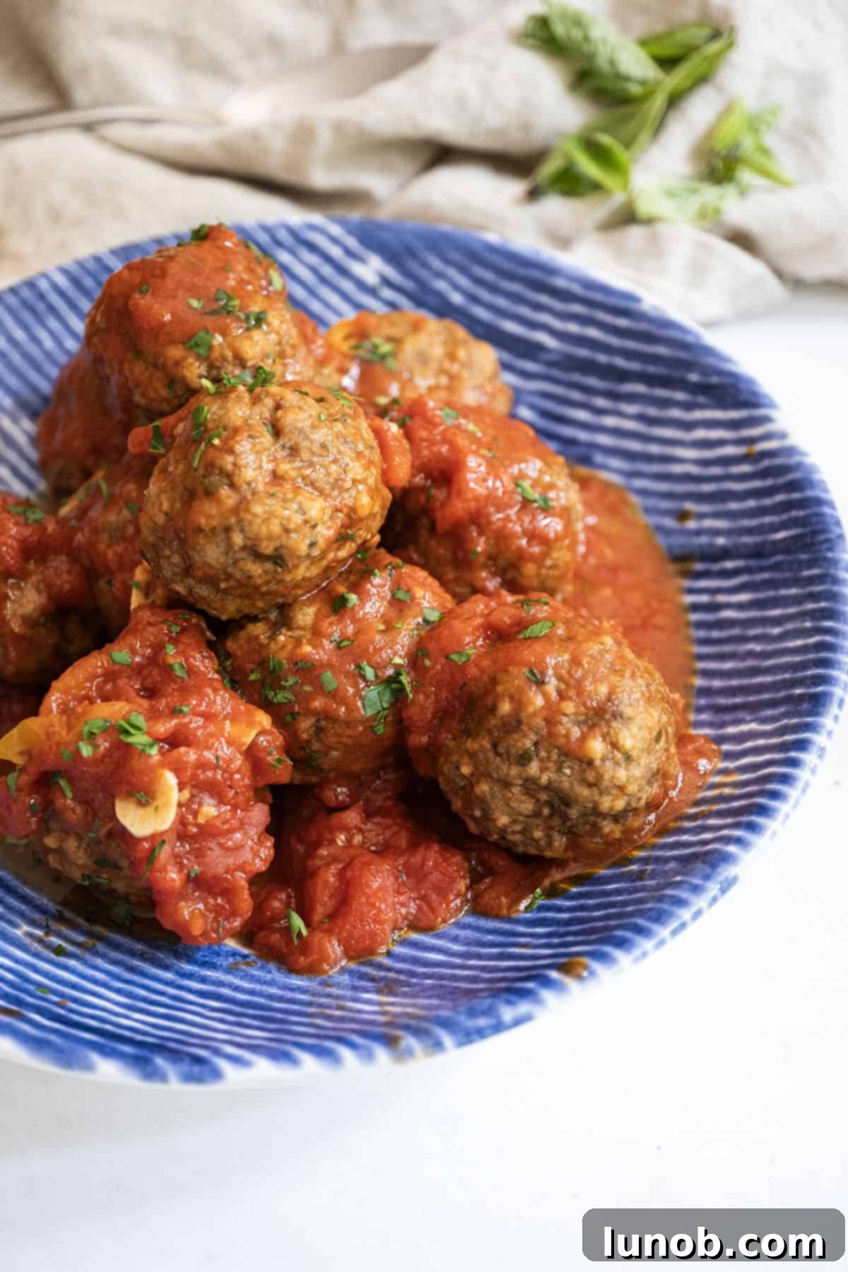 Golden-brown Italian fried meatballs generously covered in a vibrant red tomato sauce, served in a rustic bowl, ready to be enjoyed.