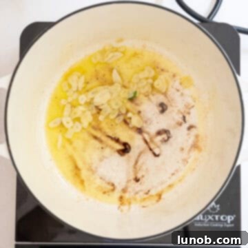 Thinly sliced garlic cloves lightly sauteing in olive oil in a pan, releasing their fragrant aroma.