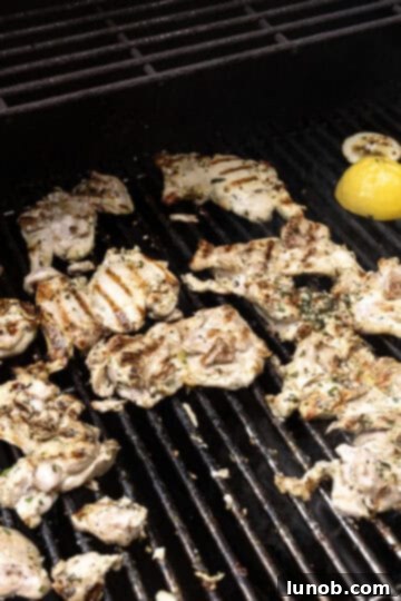 Zesty Grilled Lemon Pepper Chicken Thighs 7 Chicken thighs searing on a hot grill with a halved lemon