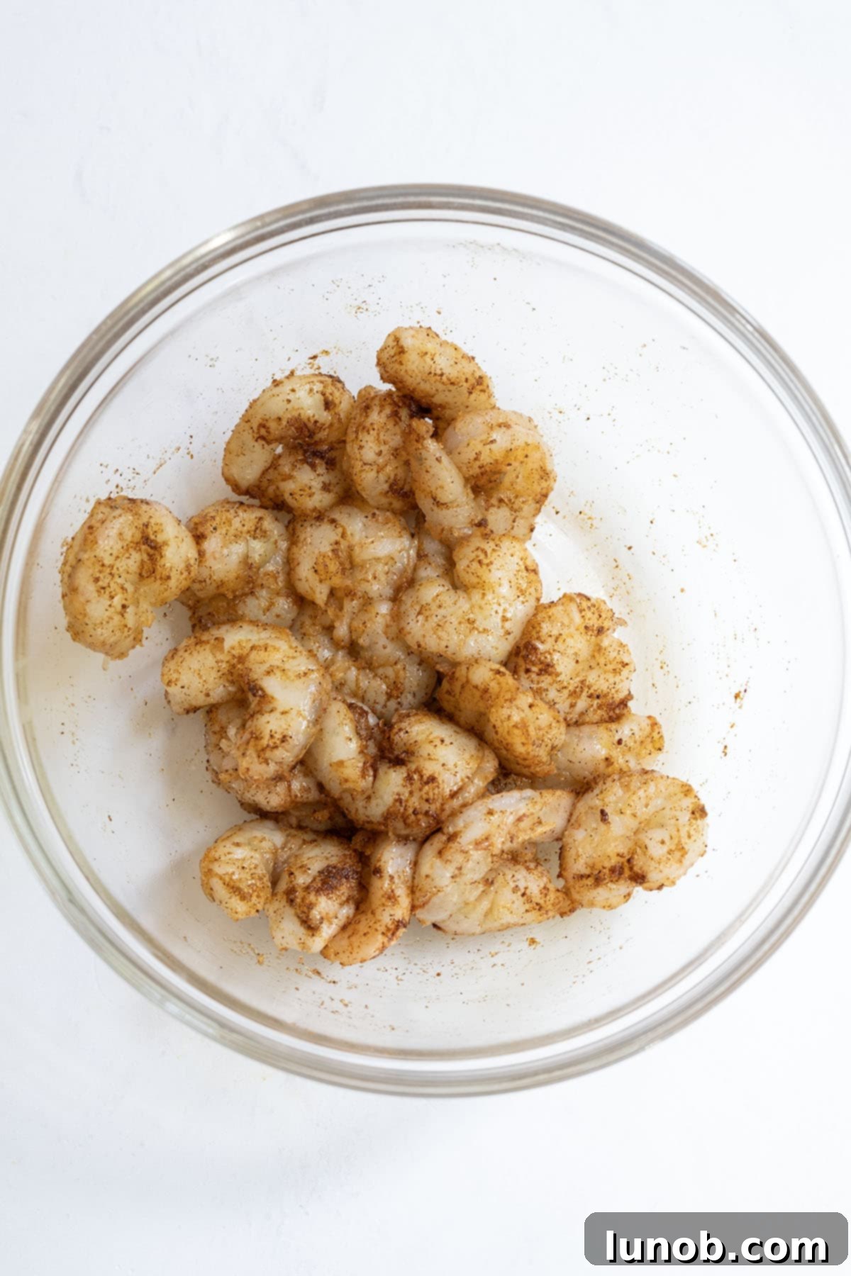 marinated shrimp in a bowl, coated in a rich blend of spices and olive oil, ready for cooking.