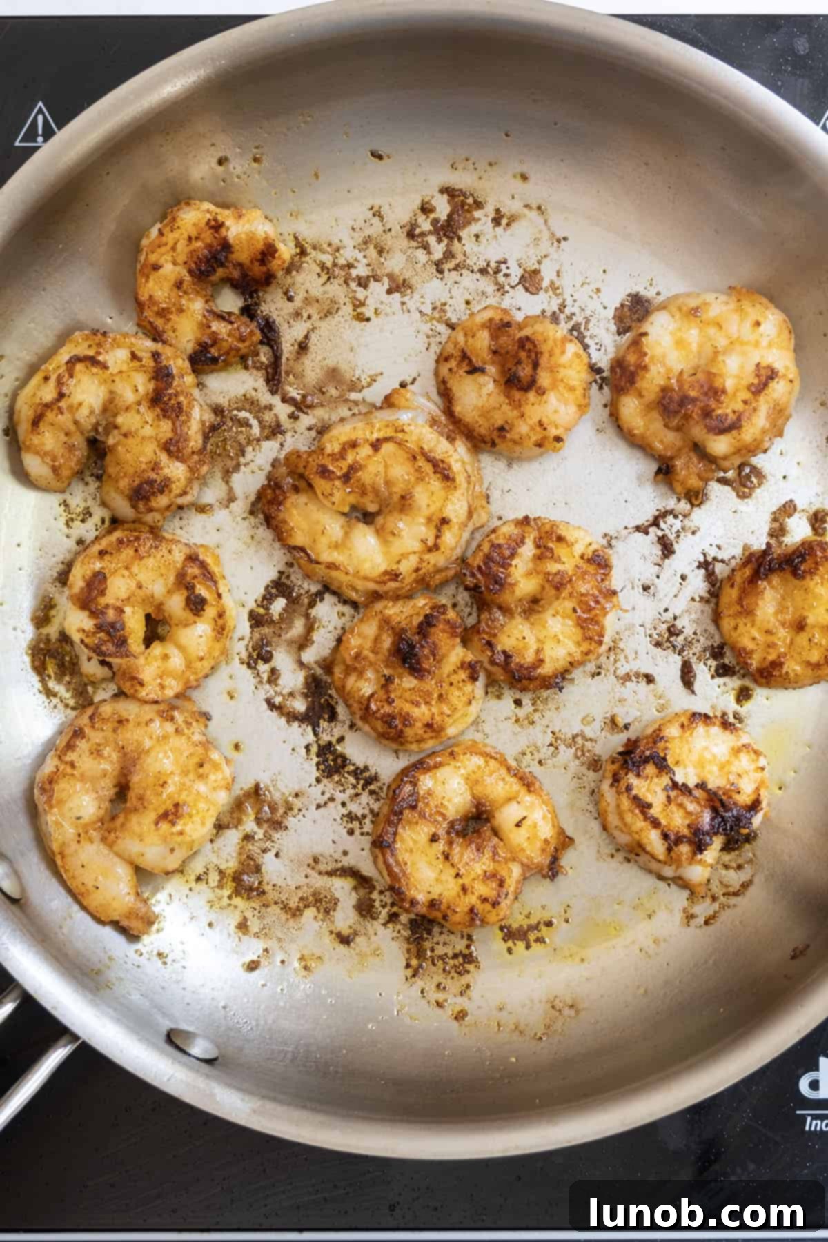 fried shrimp sizzling in a large saucepan, showing a golden-brown sear on the cooked shrimp.