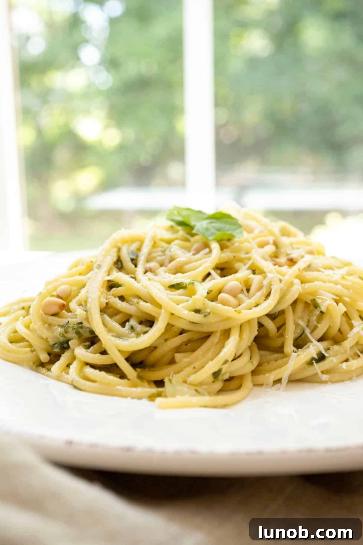 Mediterranean Artichoke Pesto Pasta 11 A large serving bowl filled with Artichoke Pesto Pasta, garnished with extra parmesan and basil, ready for a family meal.