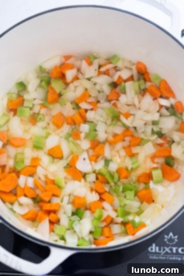 Hearty White Bean and Lentil Soup 4 Finely chopped carrots, celery, and onion gently sautéing in olive oil in a large pot, forming the aromatic soffritto base for the soup.