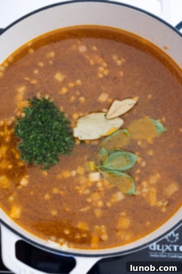 Hearty White Bean and Lentil Soup 7 A pot filled with broth, lentils, basil, parsley, and bay leaves, ready to be brought to a boil and simmered.