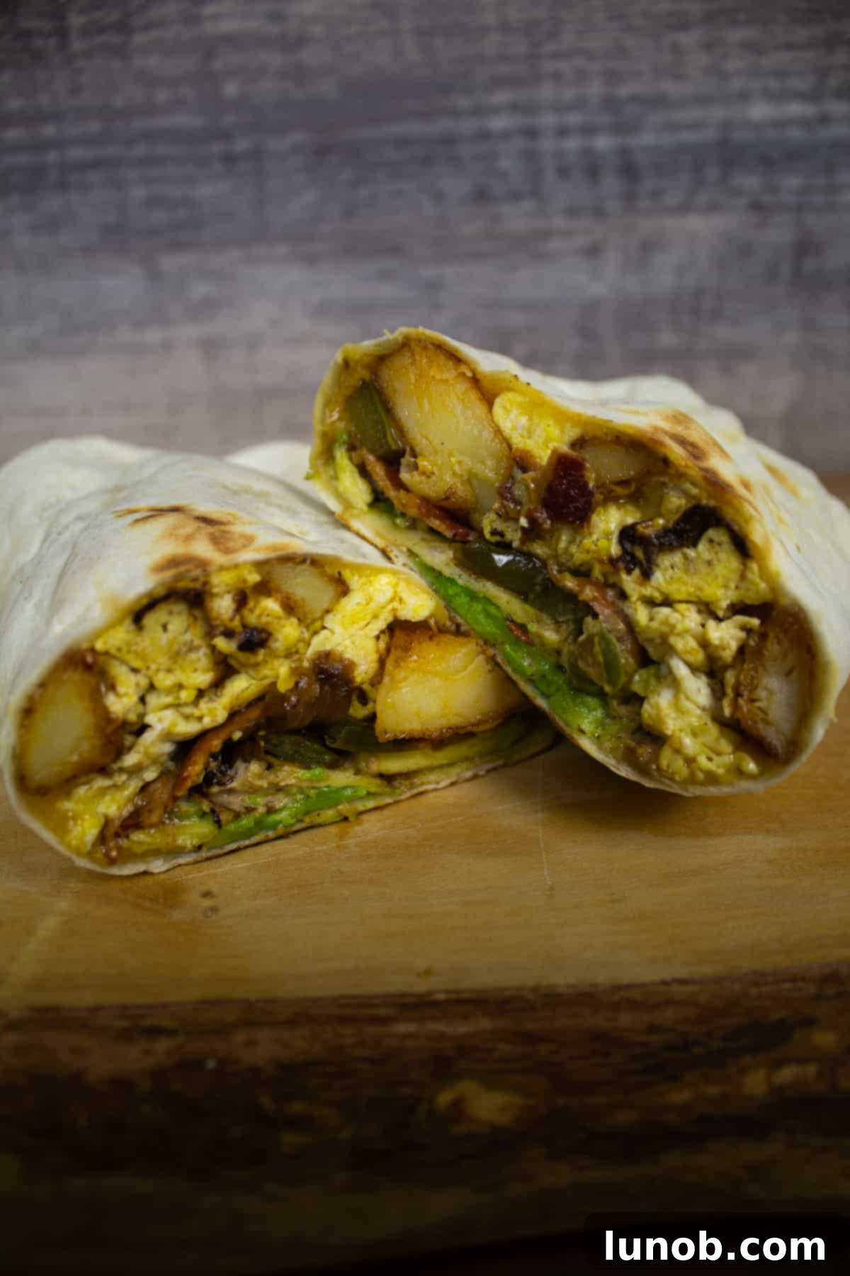 Zesty Southwest Potato Breakfast Burrito 4 A Southwest potato breakfast burrito, sliced in half to reveal layers of crispy potatoes, fluffy scrambled eggs, sautéed peppers and onions, bacon, and melted cheese.