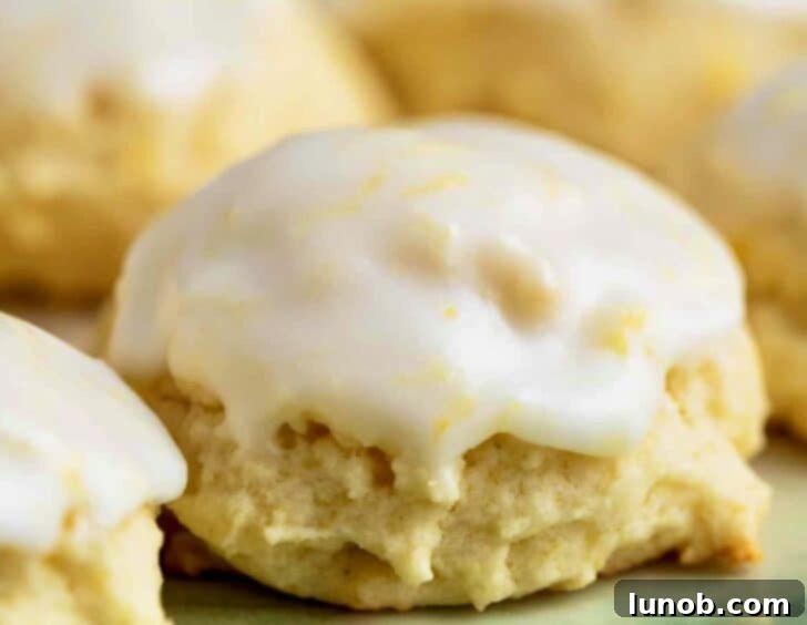 Limoncello Dokunuşlu Limonlu Ricotta Kurabiyeleri 13 A close-up of several perfectly glazed Italian lemon ricotta cookies on a serving plate