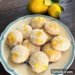 A plate of golden Italian Lemon Ricotta Cookies with Limoncello Glaze, garnished with zest