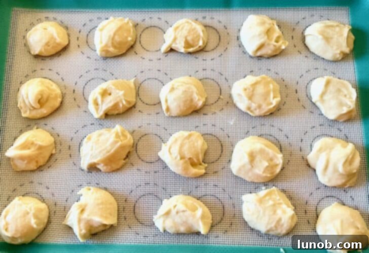 Limoncello Dokunuşlu Limonlu Ricotta Kurabiyeleri 10 Scooped portions of lemon ricotta cookie dough on a parchment-lined baking sheet
