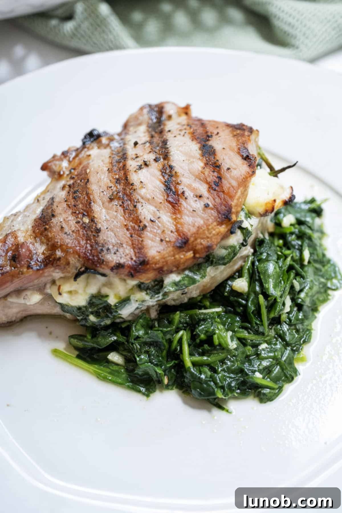 Smoky Grilled Stuffed Pork Chops 2 A grilled pork chop stuffed with feta and sauteed spinach and garlic served on more sauteed spinach.