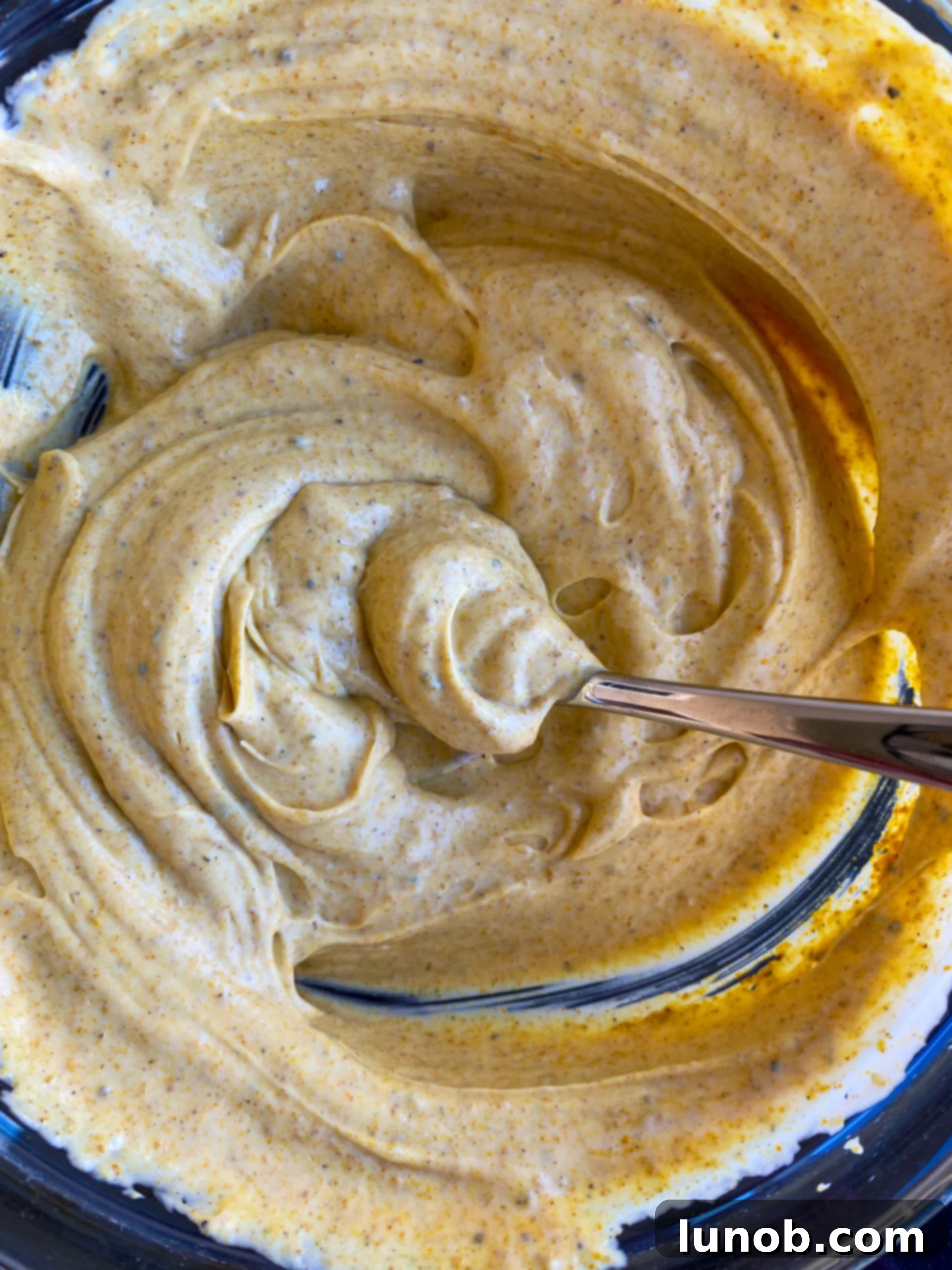 Combining curry powder with mayonnaise, sour cream, and seasonings for the dressing.