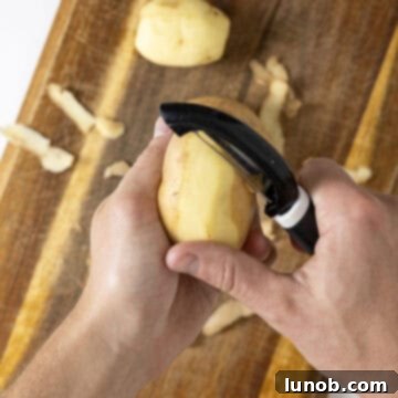 Peeling potatoes over cutting board for hash browns.