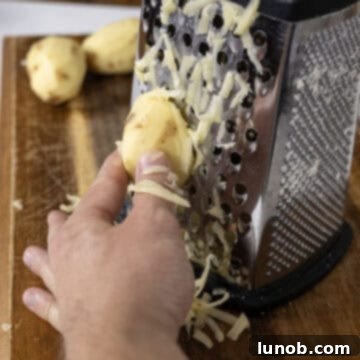 Grating potatoes on a large-hole cheese grater.