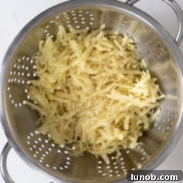 Rinsing the grated potatoes thoroughly in a colander under running water.