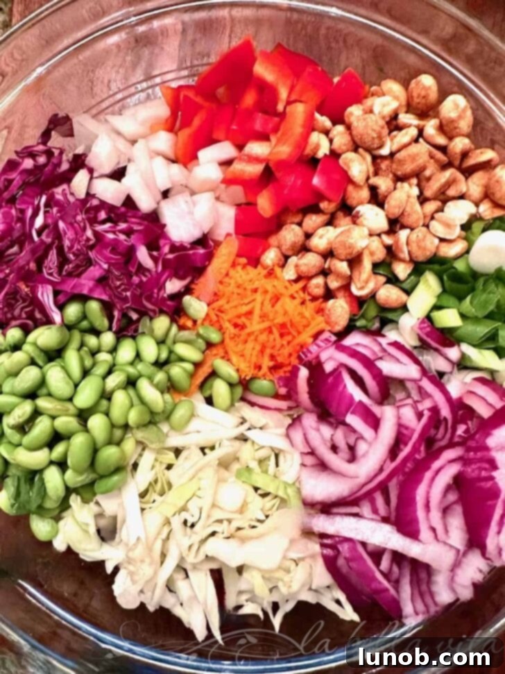 A close-up shot of the Asian Chopped Salad in a white bowl, garnished with sesame seeds and herbs, ready to be served.