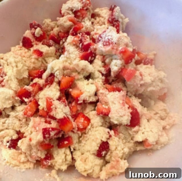 Scone dough with strawberries gently mixed in, forming a rough ball.