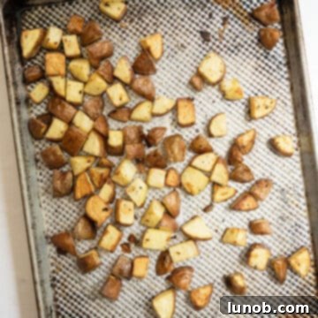 Ultimate Crispy Garlic Parmesan Potatoes 8 Golden brown crispy potatoes roasted on a baking tray.