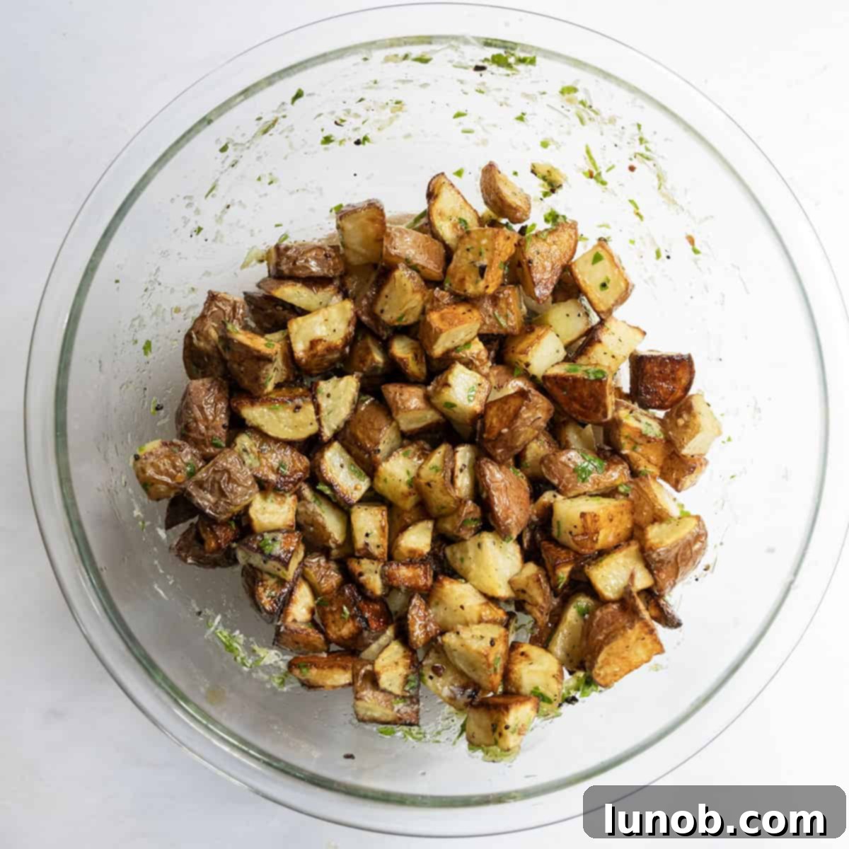 Ultimate Crispy Garlic Parmesan Potatoes 10 Crispy potatoes being tossed in garlic-parsley dressing and grated parmesan cheese.