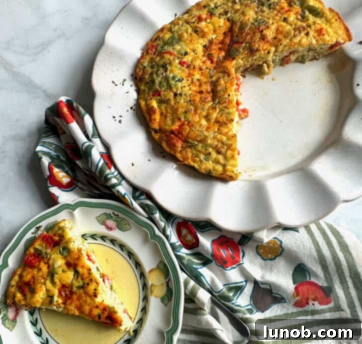 A close-up of a cheesy Italian frittata with visible peppers and tomatoes in a rustic setting.