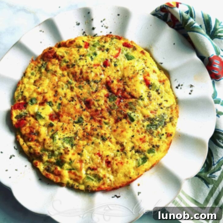 A vibrant, golden-brown cheesy Italian frittata with colorful bell peppers and tomatoes, freshly baked in a cast iron skillet.
