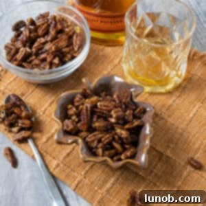 Candied pecans in 2 separate bowls next to a glass of bourbon.