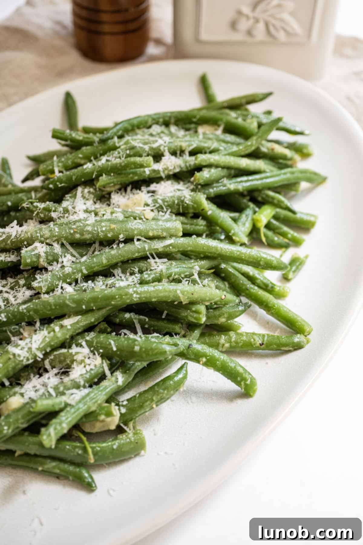Garlic Parmesan Green Beans: A Timeless Classic 2 Green beans sprinkled with parmesan on a plate, showcasing a delightful and easy side dish.