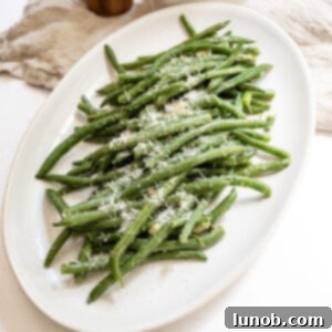 Sauteed green beans with garlic sprinkled with parmesan on a plate.