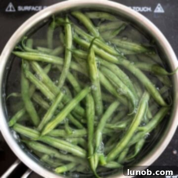 Garlic Parmesan Green Beans: A Timeless Classic 4 Green beans boiling in a pot of water, the first step in creating crisp-tender beans.