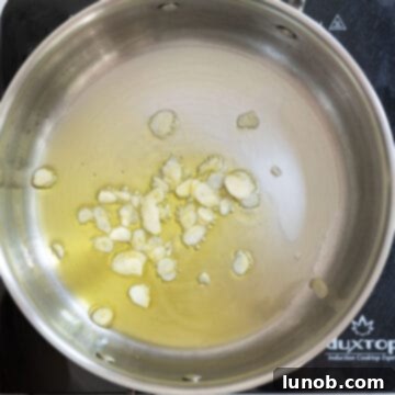 Garlic Parmesan Green Beans: A Timeless Classic 6 Sliced garlic gently sautéing in olive oil in a pan, releasing its fragrant aroma.