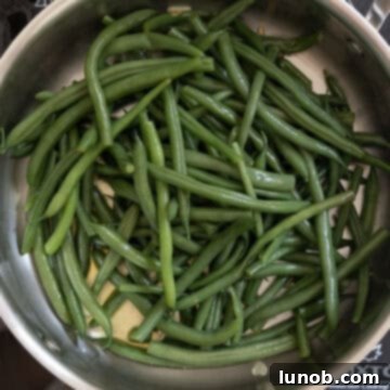Garlic Parmesan Green Beans: A Timeless Classic 7 Green beans sautéing in a pan with fragrant garlic and olive oil.