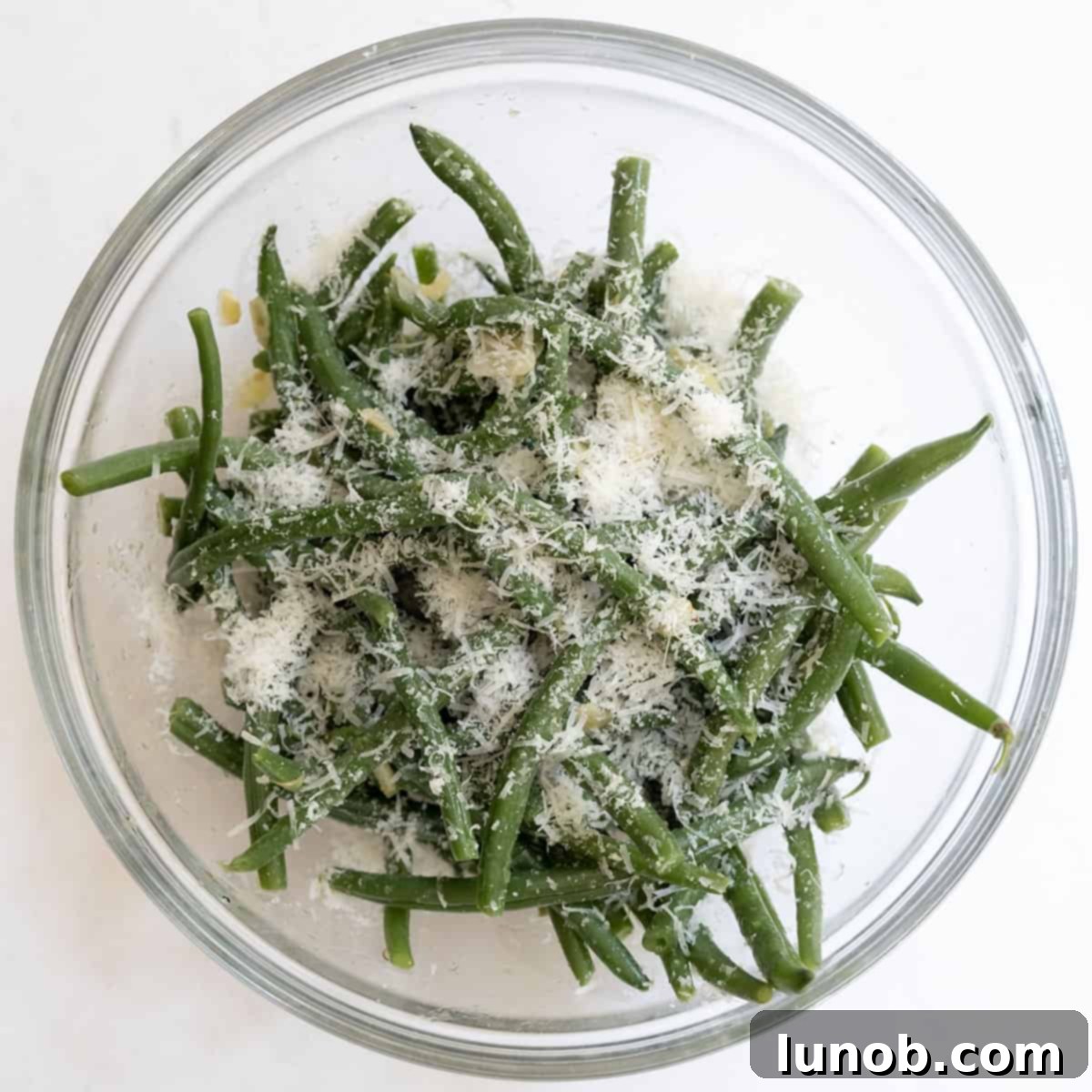 Garlic Parmesan Green Beans: A Timeless Classic 8 Cooked green beans tossed with freshly grated parmesan cheese in a bowl.