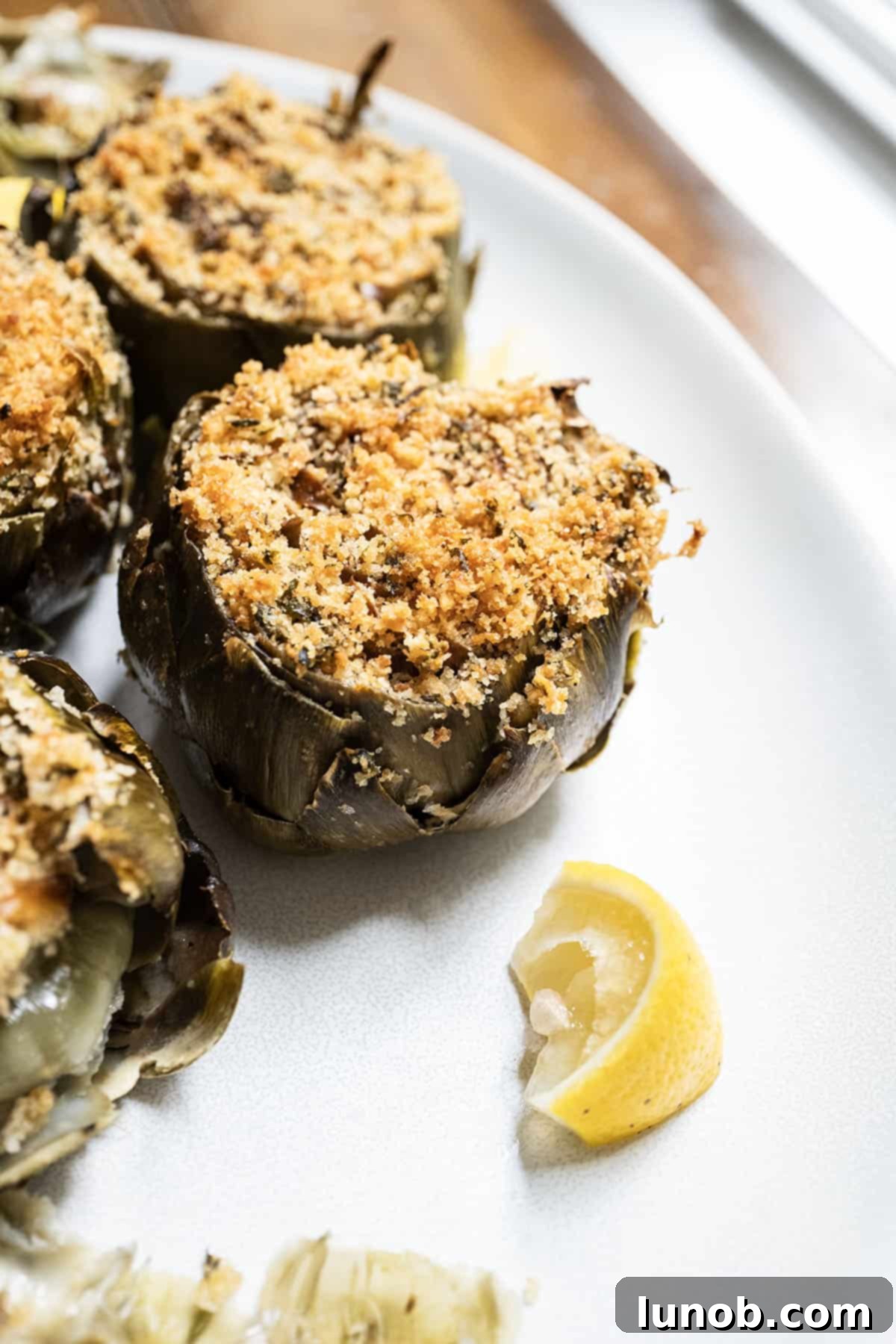 Stuffed artichokes on a plate with lemon wedges, ready to be served as an appetizer.