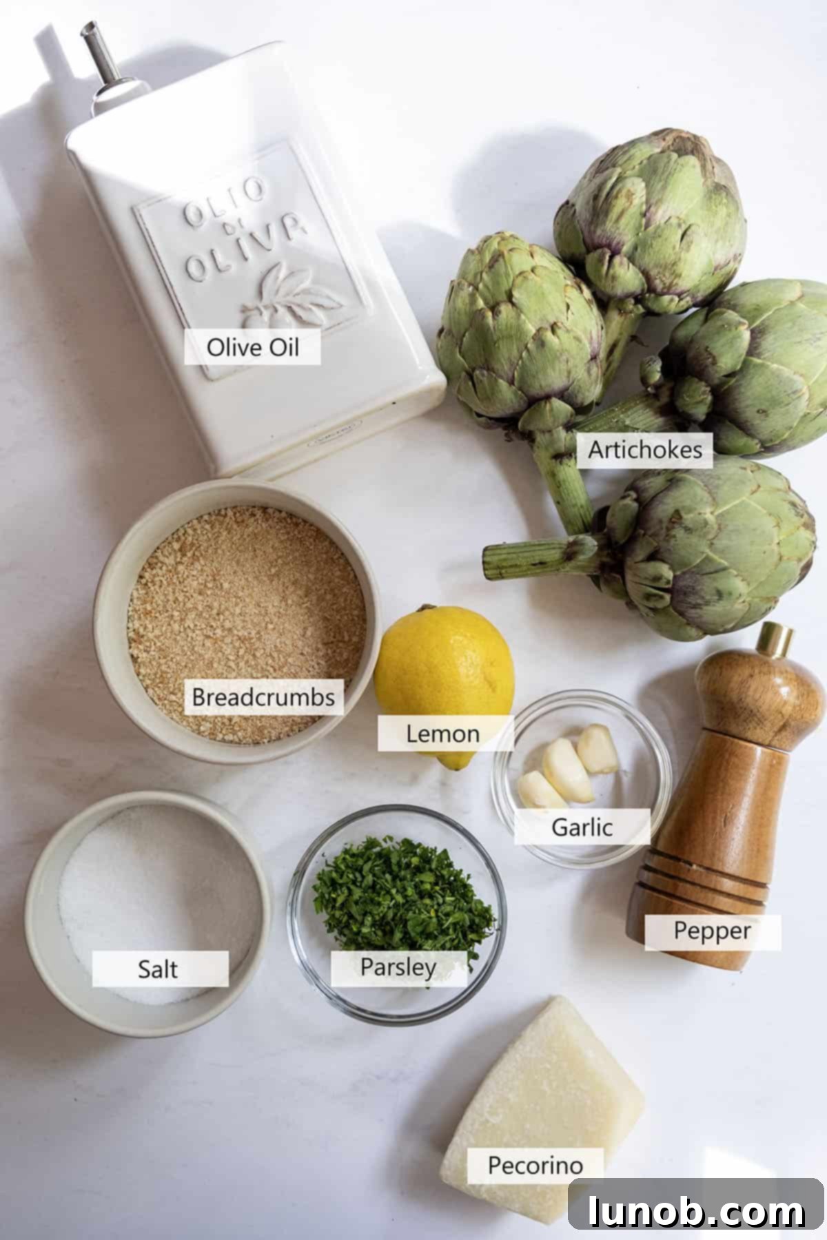 Close-up of fresh ingredients for Italian stuffed artichokes, including artichokes, breadcrumbs, cheese, and herbs.