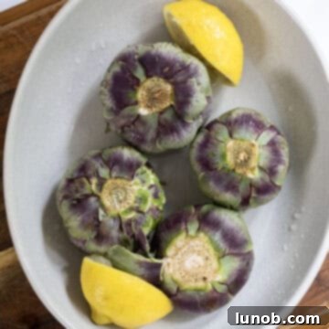 Artichokes soaking in lemon water in a bowl to prevent browning.