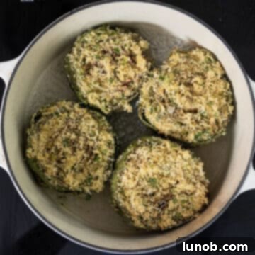 Stuffed artichokes simmering in a Dutch oven with water and olive oil.