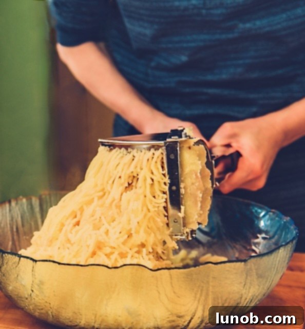 Ricing warm potatoes into a bowl for gnocchi.