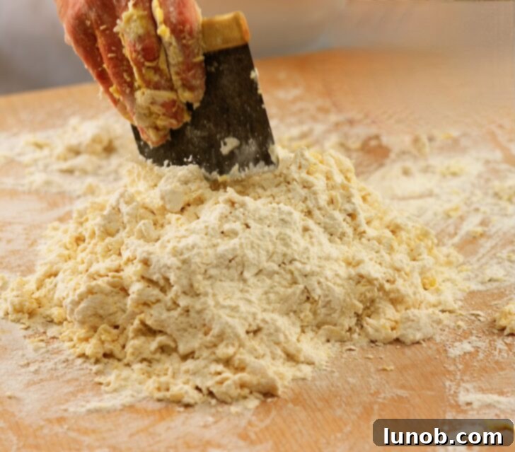 Using a bench scraper to mix gnocchi dough.