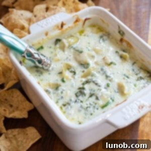Creamy No-Mayo Spinach Artichoke Dip 8 Spinach and artichoke dip in a dish with some tortilla chips next to it.