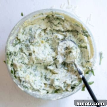 Creamy No-Mayo Spinach Artichoke Dip 5 Cheese mixed with spinach and artichokes in a bowl.