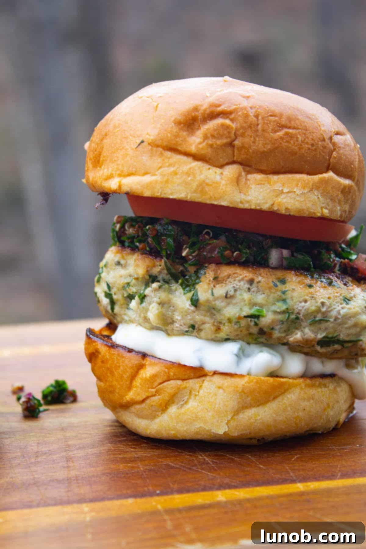 Delicious Greek chicken burger topped with creamy tzatziki and fresh tabbouleh on a toasted bun.