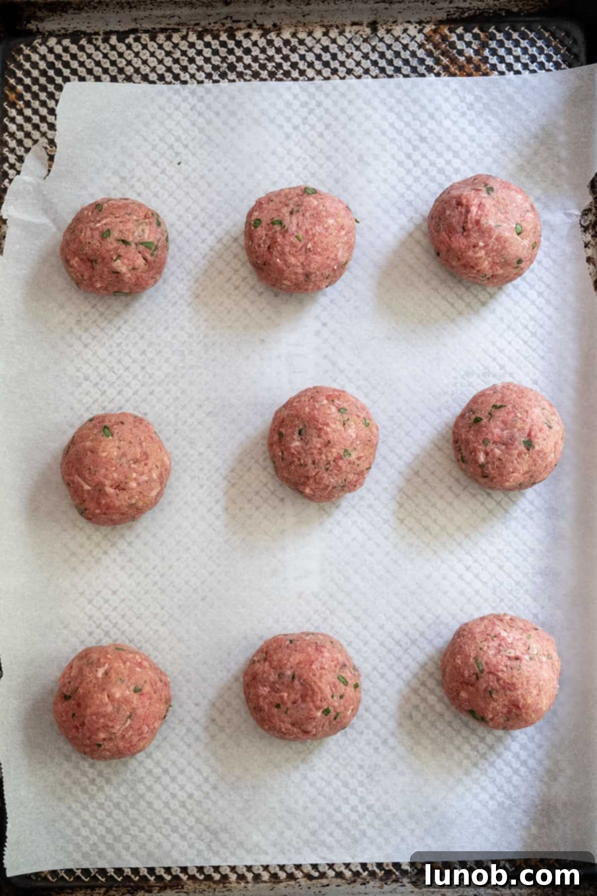 Raw meatballs on a baking sheet.