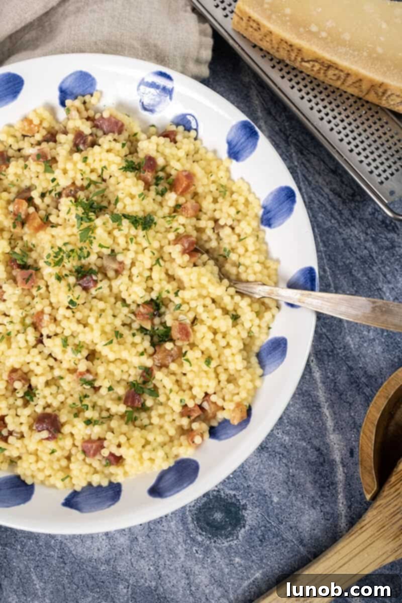 A bowl of creamy pastina carbonara with crispy pancetta and fresh parsley garnish, ready to be enjoyed as a quick and comforting meal.