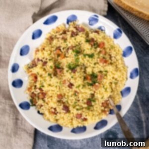 A close-up shot of creamy pastina carbonara with crispy pancetta and parsley in a bowl, highlighting the rich texture and garnishes.