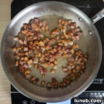 Crispy, golden-brown fried pancetta pieces resting in a pan, with rendered fat visible around them.