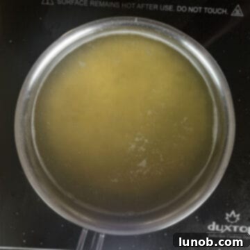 Pastina pasta boiling in a pot of water on a stove, with steam gently rising.